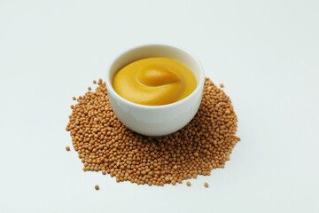 Bowl with mustard and seeds on white background