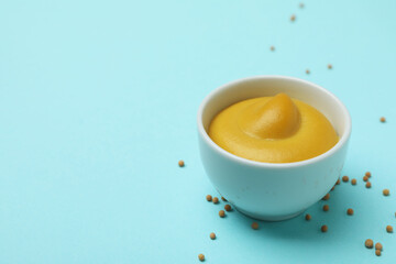 Bowl with mustard and seeds on blue background