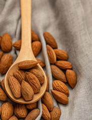 Almonds on wooden spoon on the grey napkin as background.Selective focus.Top view wit copy space.