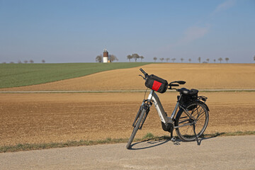 Fototapeta premium The e-bike stands near a plowed field