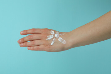 Female hand with sunscreen on blue background