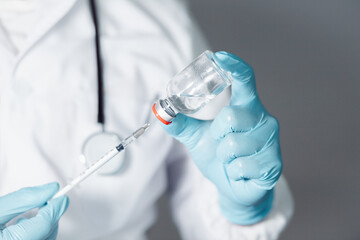 Fototapeta premium A doctor or scientist in a laboratory develops a medical vaccine. Holds a syringe with liquid vaccines to study and analyze antibody samples for new strain of COVID-19 patients in 2021. 