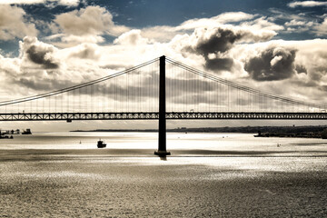 Fototapeta na wymiar 25th April Bridge in Lisbon under cloudy sky