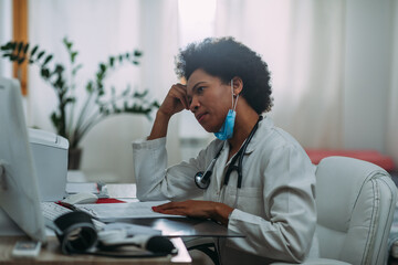 Tired female doctor using laptop at doctor's office