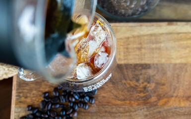Pouring coffee over ice on a doublewall clear glass 