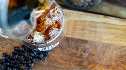 Iced coffee in a doublewall clear glass over wooden table