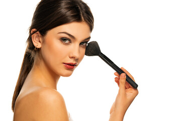 A young beautiful girl with blue eyes poses with a makeup brush