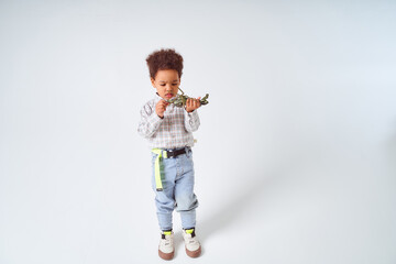 Little African-American boy sits with toy helicopter on white background