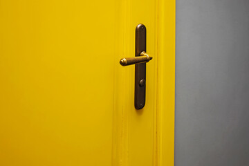 Close-up shot of yellow color door with vintage door knob.