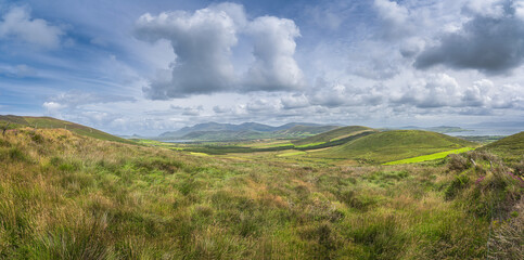 Fototapeta na wymiar Large panorama with valley, green fields, forest and lake, surrounded by hills and mountains, Dingle Peninsula, Wild Atlantic Way, Kerry, Ireland