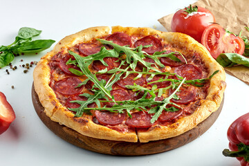 Classic Italian pepperoni pizza with spicy salami, cheese, arugula and white sauce on a plate. White background. Italian cuisine, selective focus