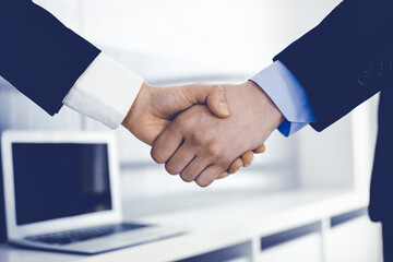 Businessman and woman shaking hands in office. Concept of handshake as success symbol in business