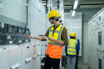 Engineer working on works on a tablet computer in switchgear room of a modern thermal power plant...