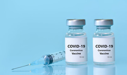Two vials with a vaccine, a syringe on a blue background.The concept of medicine, healthcare and science.Coronavirus vaccine.Copy space for text..