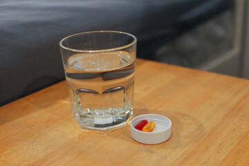 a glass of water and medicine on wooden table