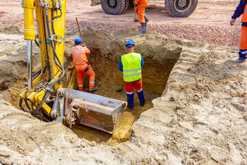 Workers are using shovels to set up right measures in square trench