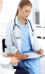 Woman - doctor consults her female patient while using clipboard and medication history record. Medicine concept