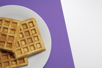 Homemade waffles, top view. on a purple and white background
