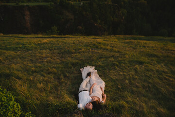 Sensual wedding couple of groom and bride lying on the green grass meadow on the hill in mountains. © WellStock