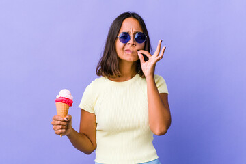 Young mixed race woman eating an ice cream with fingers on lips keeping a secret.