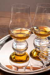 Tasting glasses of single malt scotch whisky served on steel mirror tray with reflection