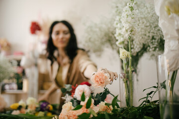Young woman florist working in her flower studio, making beautiful bouquet using fresh plants and flowers.
