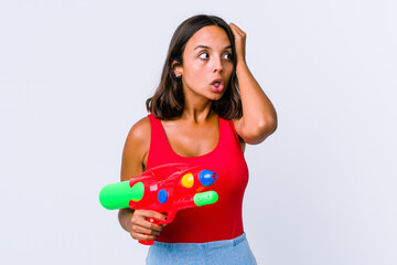 Young mixed race woman holding a water gun isolated being shocked, she has remembered important meeting.