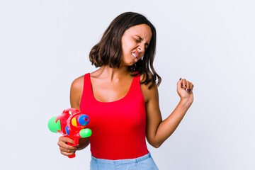 Young mixed race woman holding a water gun isolated stretching arms, relaxed position.