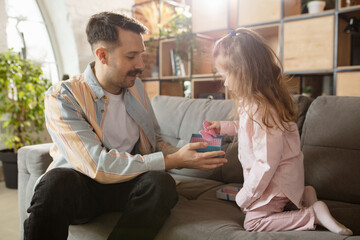 Happy father and little cute daughter at home. Family time, togehterness, parenting and happy childhood concept. Weekend with sincere emotions.