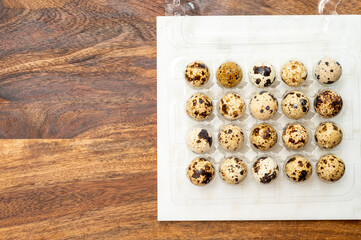 Fresh small spotted partridge eggs in tranparent plastic container