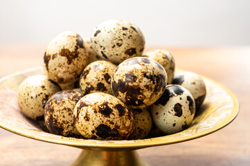 Fresh small spotted partridge eggs on bronze plate