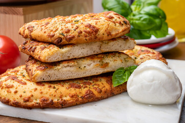 Tasty italian vegetarian food, fresh baked flat foccachia bread with white mozzarella cheese and herbs