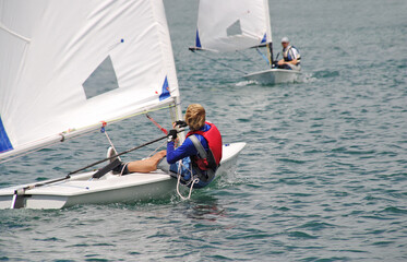 Young sailor in a small boat sailing on the lake - 427407546