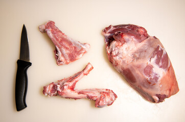 Boning a shoulder of lamb leg meat on a wooden tray, white background, Top view, High quality photo