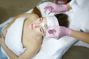Obraz na płótnie Canvas Cosmetologist does face peeling of a beautiful woman. Women s cosmetology in the beauty salon