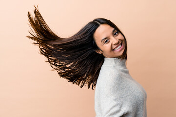 Young indian woman moving her hair isolated on beige background