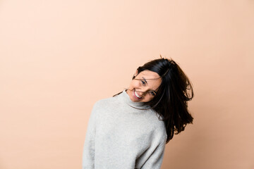 Fototapeta premium Young indian woman moving her hair isolated on beige background