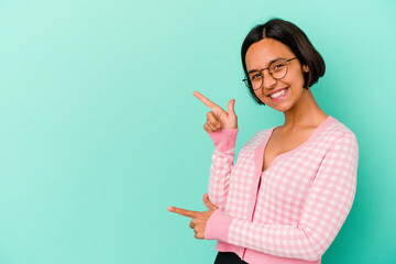 Young mixed race woman isolated on blue background pointing with forefingers to a copy space, expressing excitement and desire.