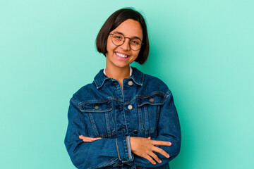 Young mixed race woman isolated on blue background who feels confident, crossing arms with determination.