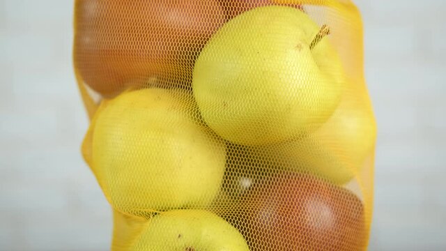 Colorful apples in a bag. Colorful white and red apples in the eco string mesh in the room.
