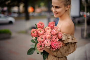 Fototapeta premium excellent view of rosebuds in flower bouquet in the hands of young smiling woman