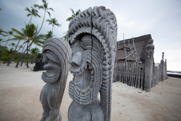 wooden carved tiki with palm trees in the back