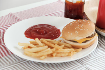 Close-ups, selective focus on ketchup in a white dish on tablecloths that are poured out of red bottles for junk food snacks, including takeaway hamburgers, french fries, snacks, and cola.