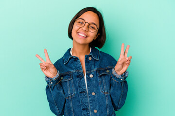 Young mixed race woman isolated on blue background showing victory sign and smiling broadly.