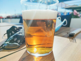 Face mask and a beer over a wooden table in a bar