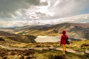 woman from behind on wooden path looking towards Lough Tay in the wicklow mountains Ireland