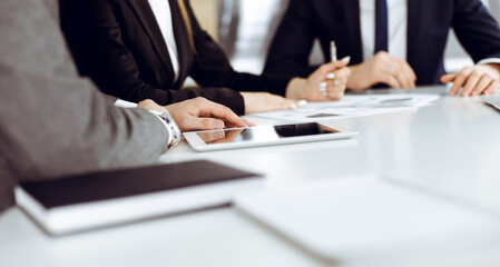 Unknown businessmen and woman sitting, working and discussing questions at meeting in modern office, close-up
