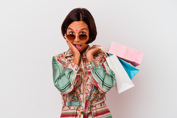 Young Indian woman shopping some clothes isolated on white background surprised and shocked.