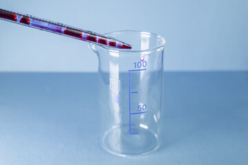 Medical laboratory. Blood from a pipette is poured into an empty test tube on a blue background. Laboratory tests.