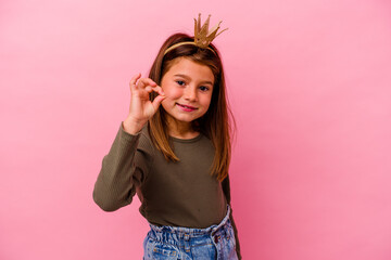 Fototapeta premium Little princess girl with crown isolated on pink background cheerful and confident showing ok gesture.